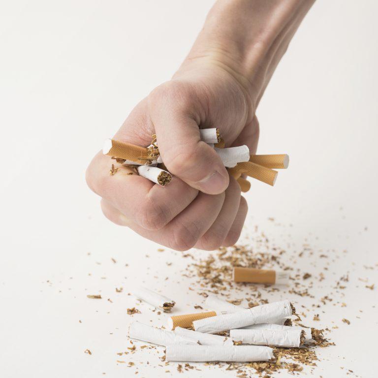 man-s-fist-creasing-cigarettes-white-background